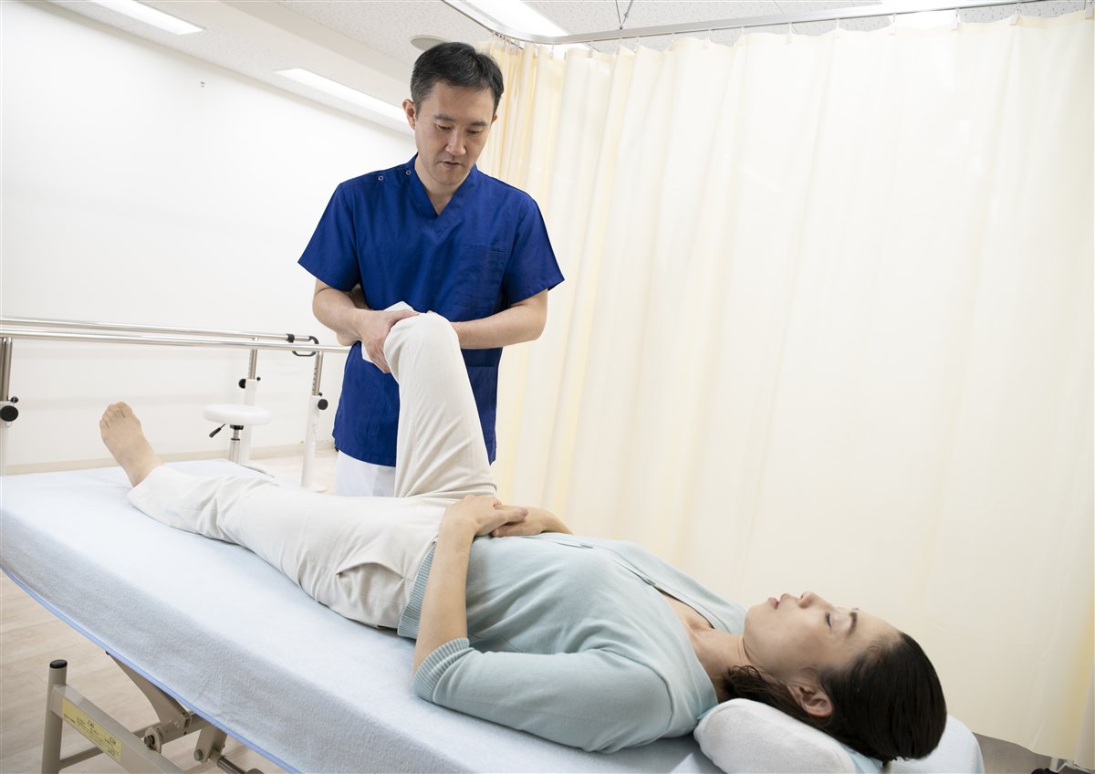 院長が患者様の脚をストレッチしながら施術している様子
